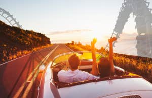 Couple driving on a road roller coaster in background
