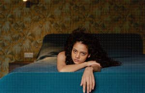 woman laying on bed, trying to sleep while anxiety overcomes her