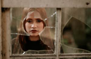 woman looking through broken window