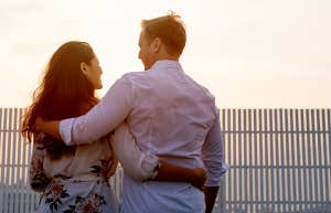 couple with arms around each other watching sunset