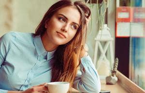 woman drinking coffee with hand in hair
