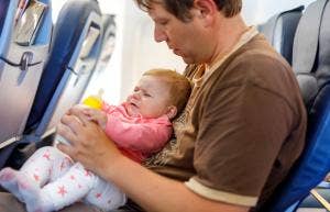 A man holds a crying baby on a plane