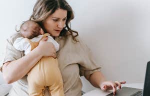 Mom holding baby while working on computer