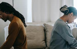 man and woman sitting back to back on bed