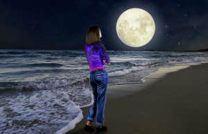 woman on the beach looking at the moon