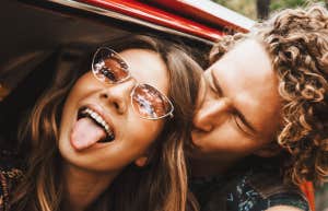 young couple with heads outside a red car being silly