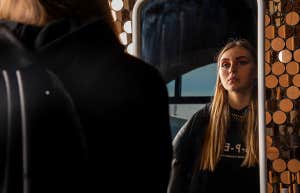 sad teenager looking in mirror