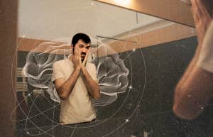 Unhappy man standing in mirror 