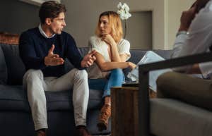 couple speaking to each other while sitting on a couch in front of a therapist