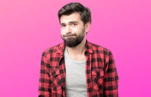 A regretful looking man stand in front of a hot pink background