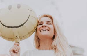 Woman with smiley face balloon looking happy and content