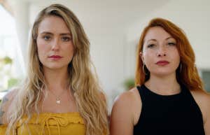 Two women looking serious, standing next to one another