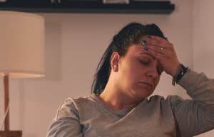 woman with hand over her face on a couch