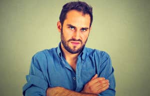 difficult man standing with his arms folded in front of his chest
