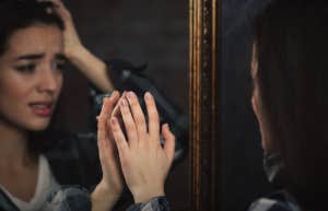 Girl looking upset at reflection in mirror 