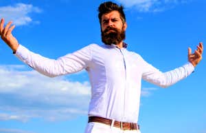 bearded man standing in front of clouds