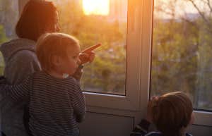 stay at home mom looking out the window with her two kids