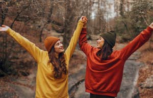 two friends with their arms up having fun outdoors