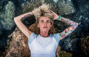 tattooed woman laying in water
