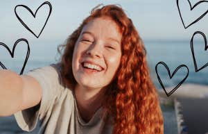 Young woman with long red hair smiling, hearts surrounding her