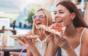 women smiling eating pizza