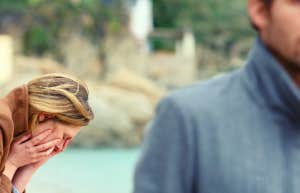 sad woman with head in her hands as man walks away