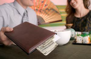 Couple paying with cash at a restaurant.