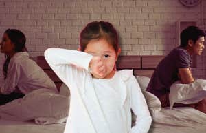 girl crying in front of arguing parents