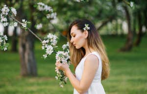 woman smelling flowers on tree