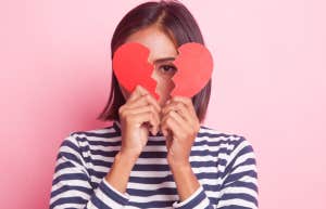 woman hiding behind broken heart