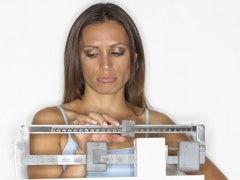 Woman taking weight on scale.